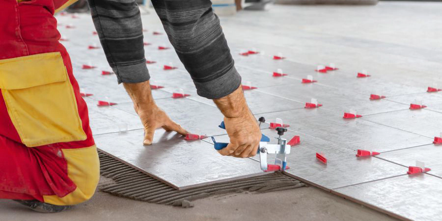 Installer using tile leveling pliers across a large floor area